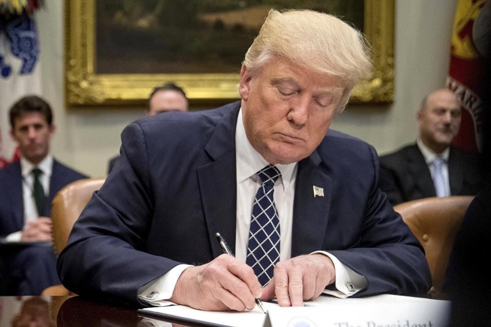 FILE - President Donald Trump signs an executive order in the Roosevelt Room of the White House in Washington, April 25, 2017. (AP Photo/Andrew Harnik, File)