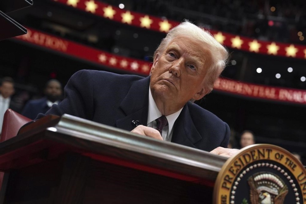 President Donald Trump signs an executive order as he attends an indoor Presidential Inauguration parade event at Capital One Arena, Monday, Jan. 20, 2025, in Washington. (AP Photo/Evan Vucci)
