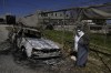 A Palestinian stands beside a torched car in the aftermath of an attack by Israeli settlers in the West Bank village of Jinsafut, Tuesday, Jan. 21, 2025. (AP Photo/Majdi Mohammed)