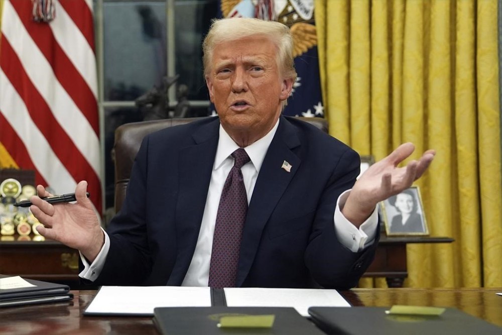 President Donald Trump talks to reporters as he signs executive orders in the Oval Office of the White House, Monday, Jan. 20, 2025, in Washington. (AP Photo/Evan Vucci)
