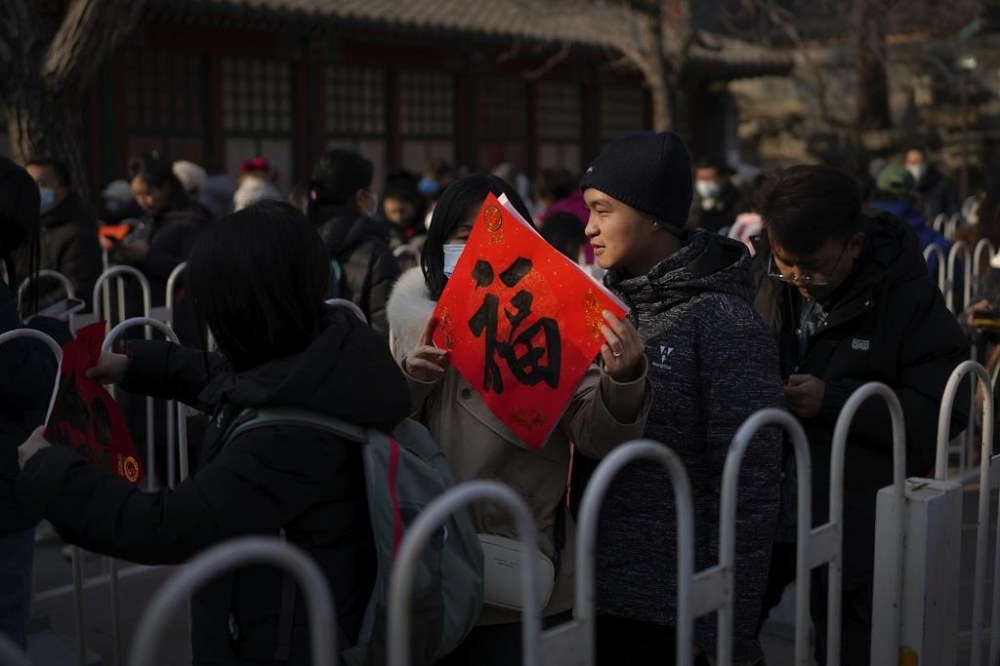 A woman holds a red paper with Chinese calligraphy