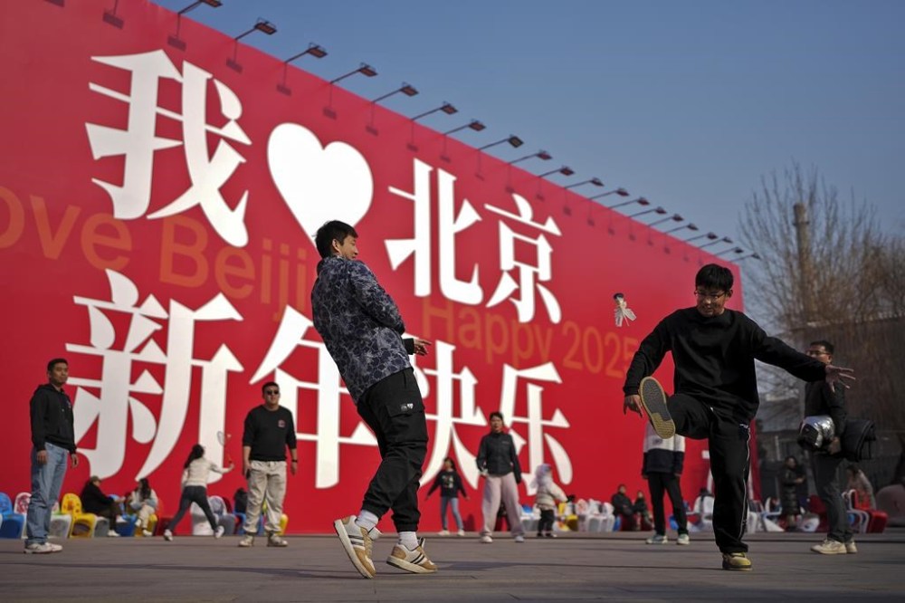 Chinese people play shutter cock near a huge display board carrying the words,