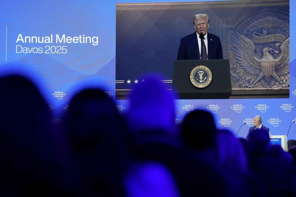 People follow a virtual speech of U.S. president Donald Trump at the Annual Meeting of World Economic Forum in Davos, Switzerland, Thursday, Jan. 23, 2025. (AP Photo/Markus Schreiber)