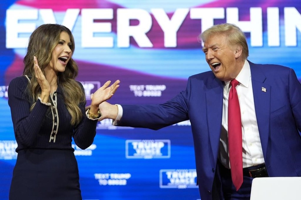 FILE - Republican presidential nominee former President Donald Trump reacts with South Dakota Gov. Kristi Noem after dancing to the song
