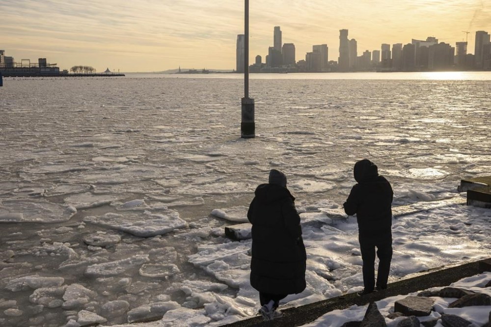People walk along the pier as ice floats on the Hudson River, Thursday, Jan. 23, 2025, in New York. (AP Photo/Yuki Iwamura)