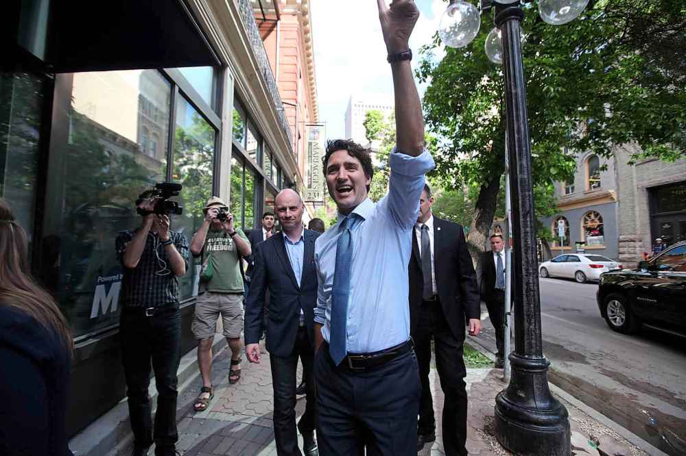 Trudeau waves to supporters as he walks down McDermot Avenue with Free Press editor Paul Samyn before an event at the Free Press News Cafe in 2016. (Ruth Bonneville / Free Press files)