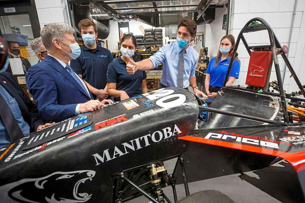 Trudeau gives a thumbs-up to MP Terry Duguid (left) while chatting with engineering students about an electric-powered race car being built at the University of Manitoba in 2023. (Mike Deal / Free Press files)