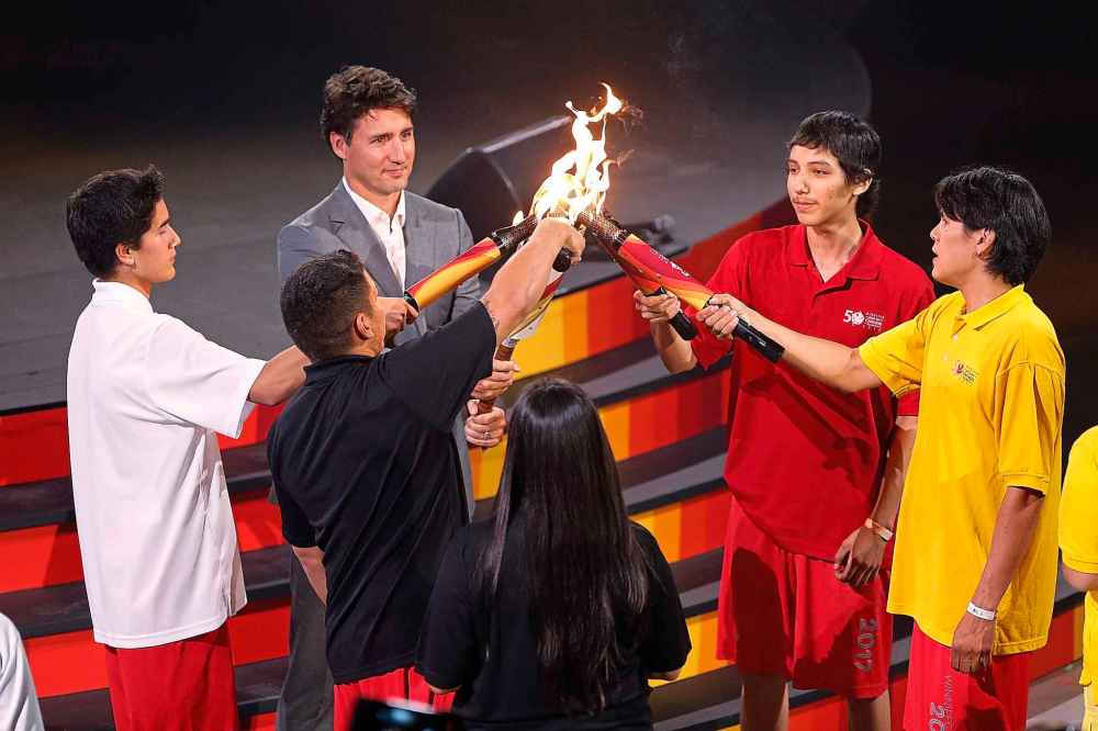 Four sacred fire torches come together to create one flame, and the torch is passed to Trudeau by four Indigenous youth at the opening ceremony for the Canada Summer Games in Winnipeg in 2017. (John Woods / The Canadian Press files)