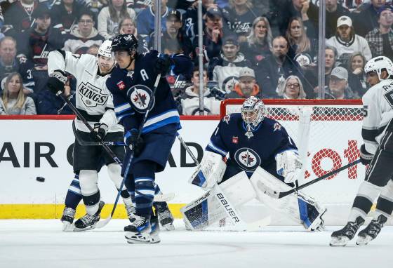 Winnipeg Jets' Mark Scheifele (second left) defends against Los Angeles Kings' Warren Foegele (left) as goaltender Eric Comrie (1) watches the puck during Friday's game. (John Woods / The Canadian Press)