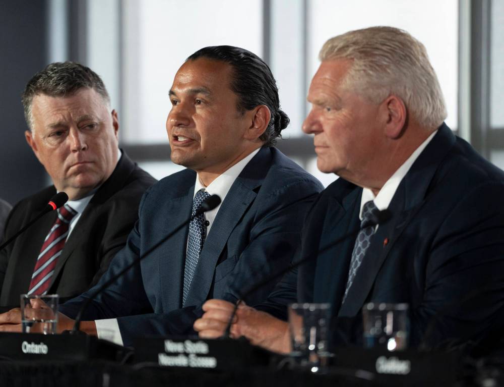 Manitoba Premier Wab Kinew, centre, speaks to reporters beside Prince Edward Island Premier Dennis King, left, and Ontario Premier Doug Ford as Canada’s premiers hold a press conference to close the Council of the Federation meetings in Halifax on Wednesday. (Darren Calabrese / The Canadian Press