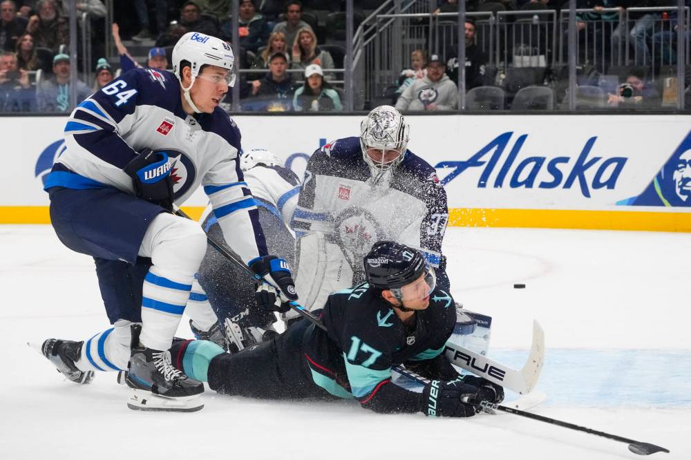 Lindsey Wasson / The Associated Press files
Jets defenceman Logan Stanley ties up Kraken forward Jaden Schwartz in front of Connor Hellebuyck’s net.