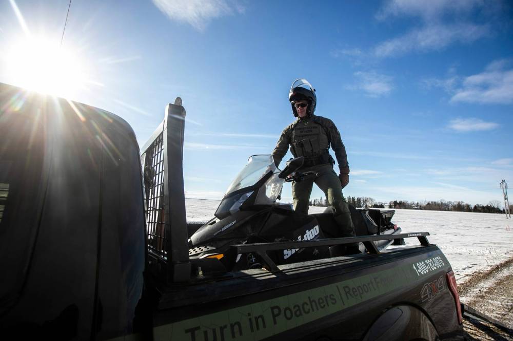 MIKAELA MACKENZIE / FREE PRESS
Conservation officer Nick Woroniuk loads a snowmobile onto conservation truck at the Canada-U.S. border near Emerson on Monday.