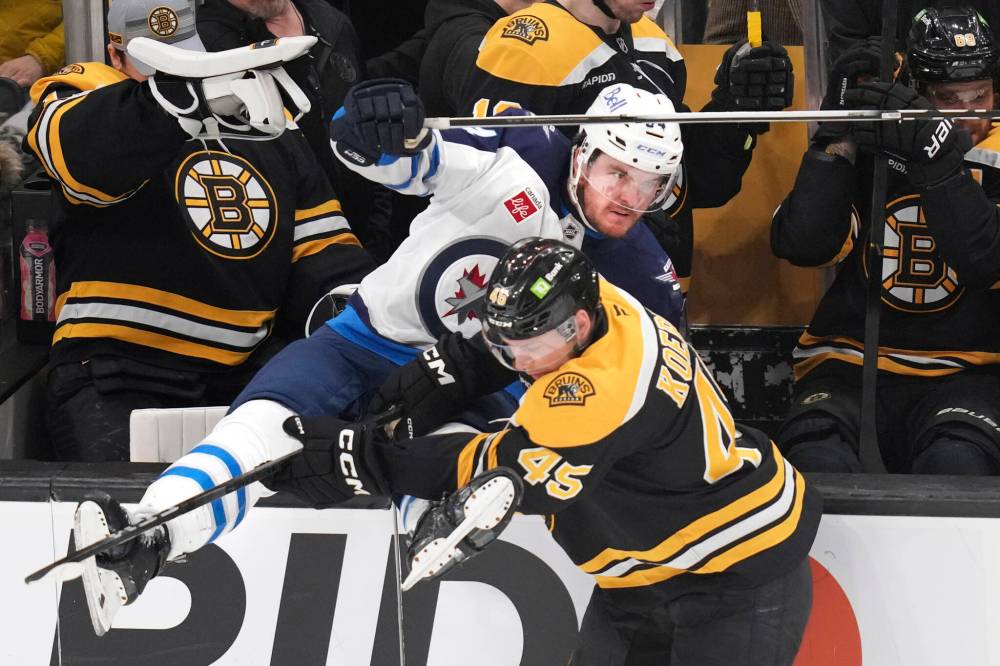 Charles Krupa / The Associated Press
Winnipeg Jets defenceman Dylan Samberg, left, is checked into the Boston bench by Bruins left wing Cole Koepke in the second period.