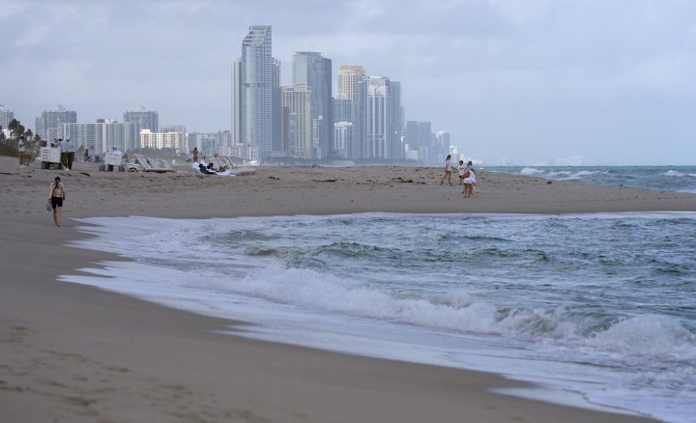 Snowbirds are scrambling to sell their homes in Florida as a weak loonie and high insurance costs drive a Canadian exodus from the sunshine state. People walk along the beach in Surfside, Fla. on Tuesday, Dec. 17, 2024. THE CANADIAN PRESS/AP/Lynne Sladky