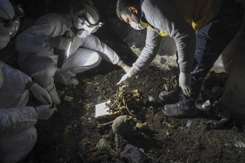 Syrian civil defense workers, known as the White Helmets, collect human remains found in two separate basements in Sbeneh, outskirts of Damascus, Syria, Tuesday, Jan. 28, 2025. According to the White Helmets, the charred remains belong to at least 26 victims of the Bashar Assad regime. (AP Photo/Omar Albam)
