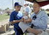 FILE - Former Major League Baseball Commissioner Fay Vincent signs an autograph for Louis Carrons, 12, of Rancho Cucamonga, Calif., during Los Angeles Dodgers baseball spring training in Vero Beach, Fla., March 1, 2006. (AP Photo/Richard Drew, File)