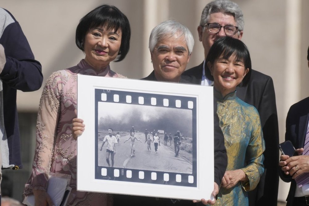 FILE - Pulitzer Prize-winning photographer Nick Ut, center, flanked by Kim Phuc, left, holds the