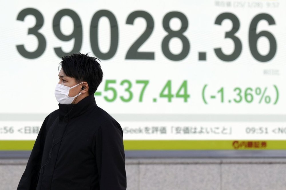 A person walks in front of an electronic stock board showing Japan's Nikkei index at a securities firm Tuesday, Jan. 28, 2025, in Tokyo. (AP Photo/Eugene Hoshiko)