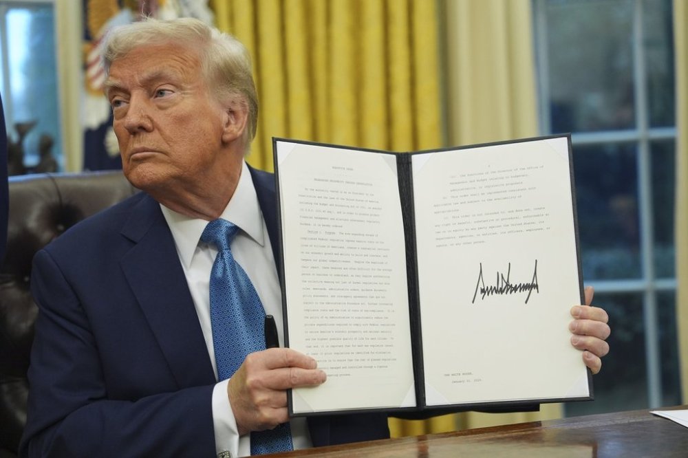 President Donald Trump holds a signed executive order on deregulation in the Oval Office of the White House, in Washington, Friday, Jan. 31, 2025. THE CANADIAN PRESS/AP-Evan Vucci