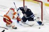 Winnipeg Jets' goaltender Eric Comrie (1) makes a save on Calgary Flames' Blake Coleman (20) during the first period of their NHL hockey game in Winnipeg, Sunday, Jan. 26, 2025. THE CANADIAN PRESS/Fred Greenslade