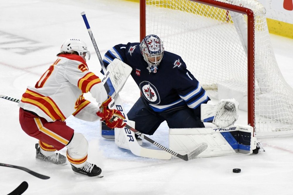 Winnipeg Jets' goaltender Eric Comrie (1) makes a save on Calgary Flames' Blake Coleman (20) during the first period of their NHL hockey game in Winnipeg, Sunday, Jan. 26, 2025. THE CANADIAN PRESS/Fred Greenslade