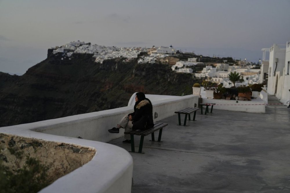 A tourist sits at Firostefani as Greek authorities are taking emergency measures in response to intense seismic activity on the popular Aegean Sea holiday island of Santorini, southern Greece, Monday, Feb. 3, 2025. (AP Photo/Petros Giannakouris)