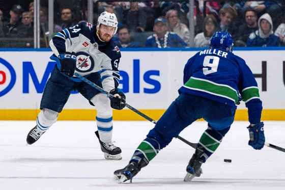 Winnipeg Jets' Dylan Samberg (54) passes the puck in front of Vancouver Canucks' J.T. Miller (9) during a game last season. The two teams face off tonight, Puck drop is 7 p.m. (Ethan Cairns / The Canadian Press files)