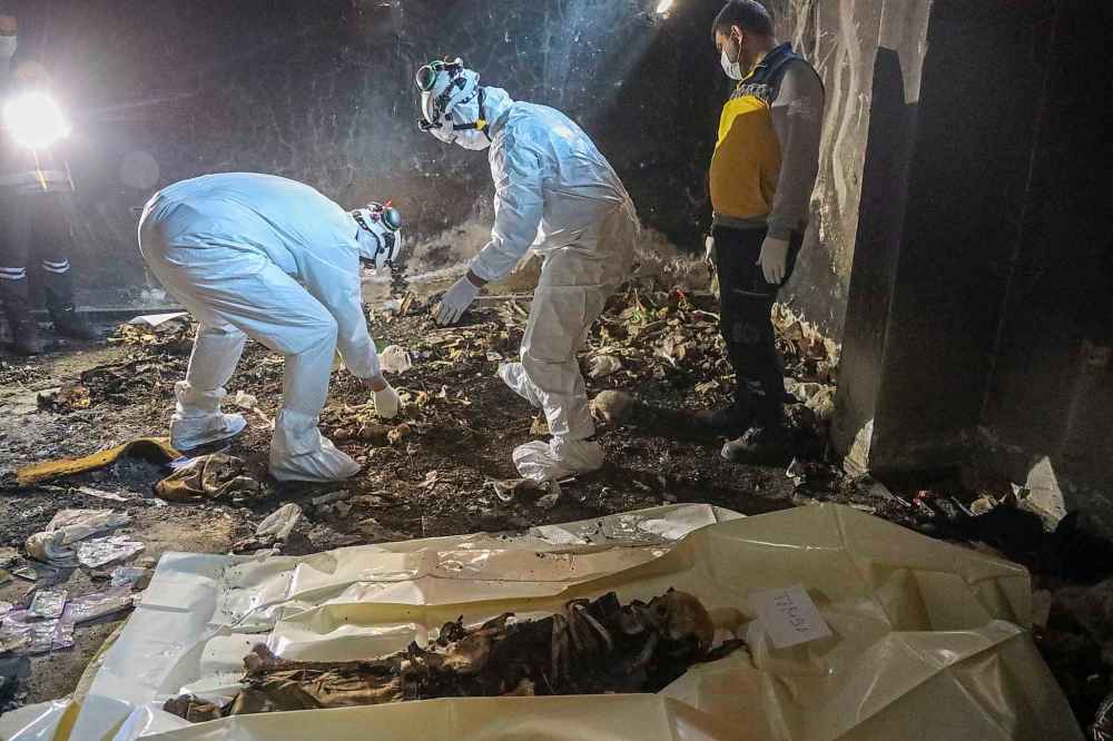 Syrian civil defense workers, known as the White Helmets, collect human remains found in two separate basements in Sbeneh, outskirts of Damascus, Syria, Tuesday, Jan. 28, 2025. According to the White Helmets, the charred remains belong to at least 26 victims of the Bashar Assad regime. (AP Photo/Omar Albam)