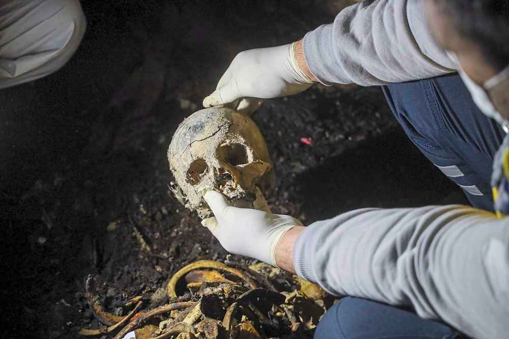 A Syrian civil defense worker, known as a White Helmet, holds a skull while inspecting human remains found in two separate basements in Sbeneh, outskirts of Damascus, Syria, Tuesday, Jan. 28, 2025. According to the White Helmets, the charred remains belong to at least 26 victims of the Bashar Assad regime. (AP Photo/Omar Albam)