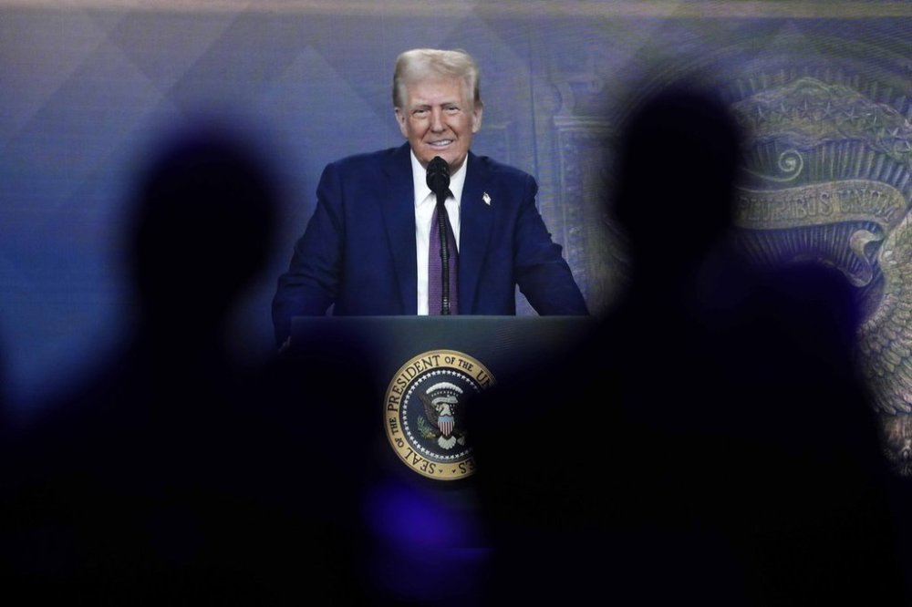 FILE - People follow a virtual speech of President Donald Trump at the annual meeting of the World Economic Forum in Davos, Switzerland, Jan. 23, 2025. (AP Photo/Markus Schreiber, File)