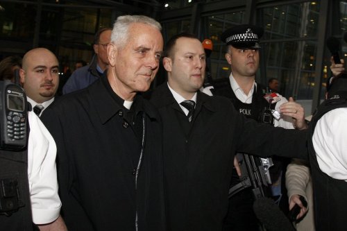FILE - Bishop Richard Williamson, foreground left, is escorted out of Heathrow airport by police and security officers after arriving on a flight from Argentina, in London, Wednesday, Feb. 25, 2009. (AP Photo/Kirsty Wigglesworth), File)