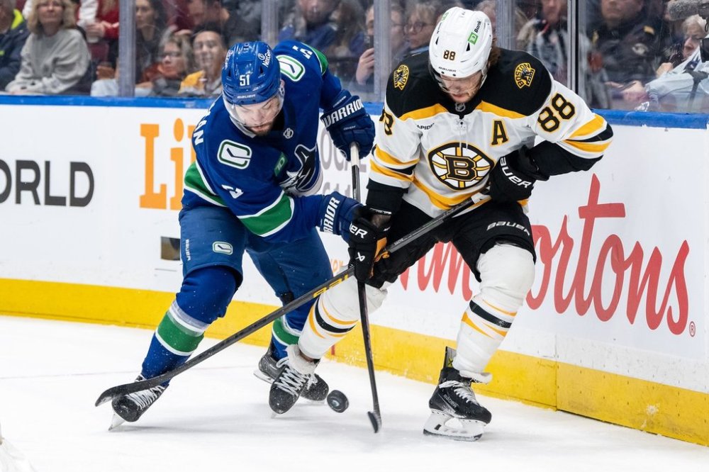 Vancouver Canucks' Mark Friedman (51) and Boston Bruins' David Pastrnak (88) vie for the puck during the first period of an NHL hockey game in Vancouver, B.C., Saturday, Dec. 14, 2024. THE CANADIAN PRESS/Ethan Cairns