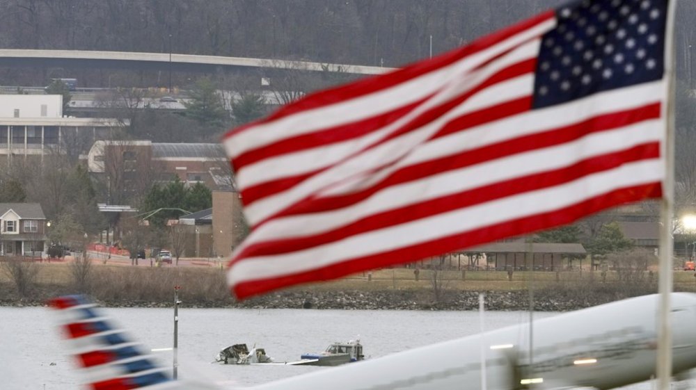 Search efforts are seen around a wreckage site of a deadly midair collision between an American Airlines jet and an Army helicopter, in the Potomac River near Ronald Reagan Washington National Airport, Friday, Jan. 31, 2025, in Arlington, Va., as an American Airlines jet lifts off from the airport, foreground. (AP Photo/Alex Brandon)