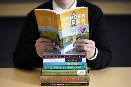 FILE - Amanda Darrow, director of youth, family and education programs at the Utah Pride Center, poses with books that have been the subject of complaints from parents, including 