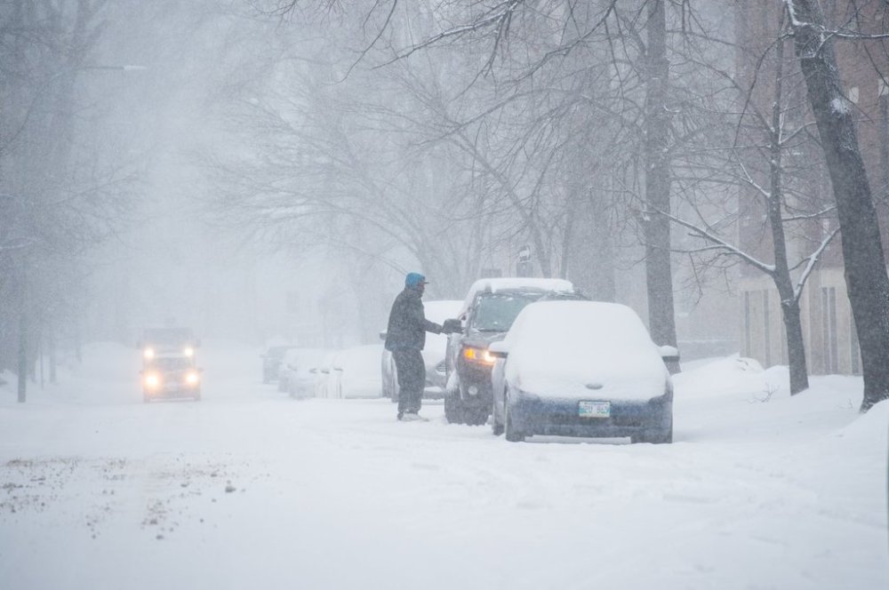 A man sweeps snow off of his car parked on Edmonton Street in Winnipeg on Wednesday, April 13, 2022 during a spring snowstorm. THE CANADIAN PRESS/Mike Sudoma
