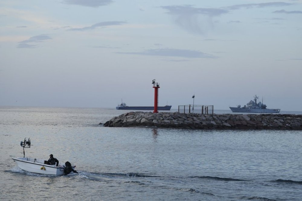 An Italian navy ship, right, with 49 migrants approaches the port, in the third such attempt following hurdles by Italian courts, in Shengjin, northwestern Albania, Tuesday, Jan. 28, 2025. (AP Photo/Vlasov Sulaj)