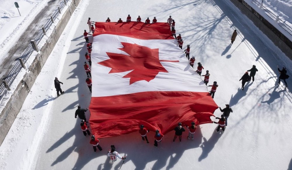 Local youth skate with a large Canadian flag on the Rideau Canal to launch celebrations marking National Flag of Canada Day on Friday, Feb. 14, 2025 in Ottawa. THE CANADIAN PRESS/Adrian Wyld