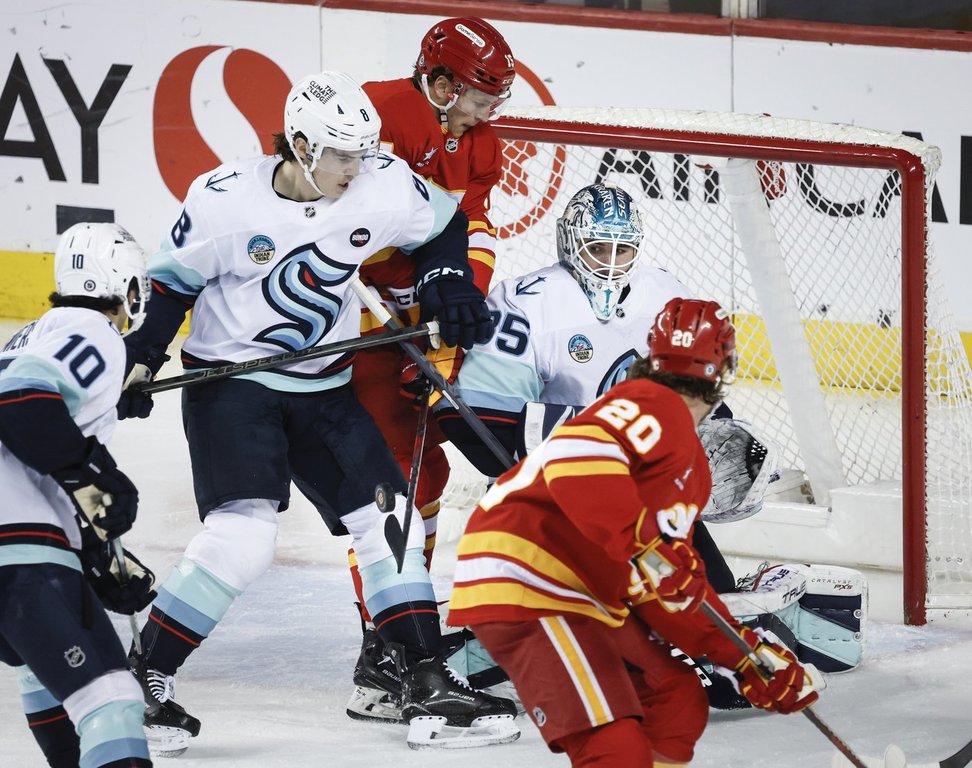 Seattle Kraken goalie Joey Daccord, centre right, follows the puck as Cale Fleury, second left, checks Calgary Flames' Dryden Hunt, centre left, during second period NHL hockey action in Calgary on Saturday, Feb. 8, 2025.THE CANADIAN PRESS/Jeff McIntosh