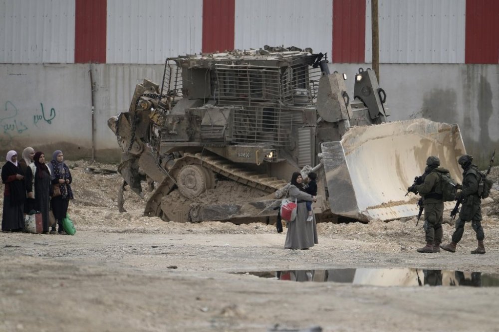 Israeli soldiers check the identification cards of Palestinians while they evacuate their homes in the West Bank refugee camp of Nur Shams, near Tulkarem, while the Israeli military operation continues in the area on Tuesday, Feb. 11, 2025. (AP Photo/Majdi Mohammed)