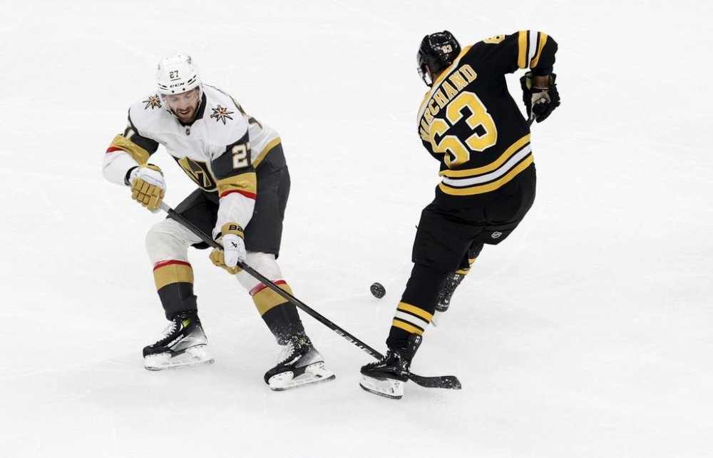 Vegas Golden Knights defenseman Shea Theodore (27) and Boston Bruins left wing Brad Marchand (63) battle for the puck during the second period of an NHL hockey game, Saturday, Feb. 8, 2025, in Boston. (AP Photo/Mark Stockwell)