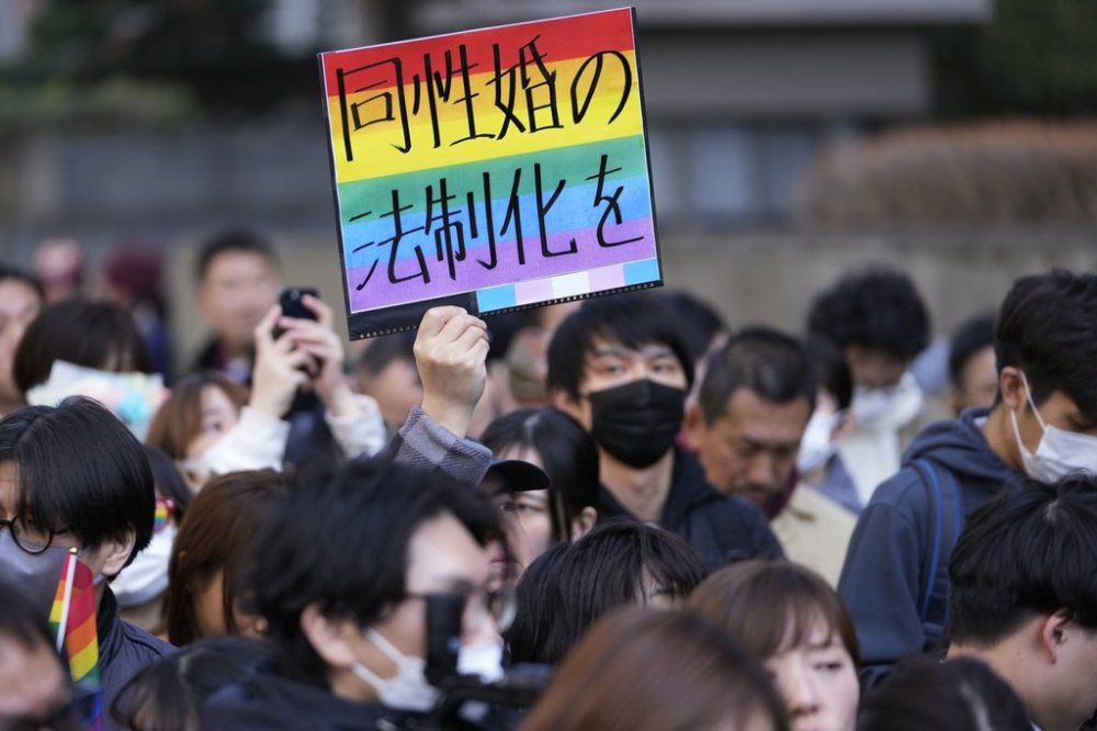 FILE - A supporter for the LGBTQ+ community holds up a poster reading