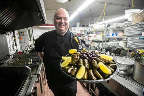 MIKAELA MACKENZIE / FREE PRESS
                                Helios owner Nick Douklias shows off a tray of dolmadakia (stuffed grape leaves) at the Norwood restaurant which will celebrate its 10th anniversary later this year.