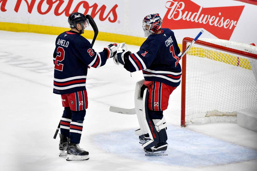 Fred Greenslade / THE CANADIAN PRESS
Dylan DeMelo (left) congratulates Eric Comrie Tuesday night after the goaltender recorded his first shutout of the season in the Jets 3-0 win over the Carolina Hurricanes.