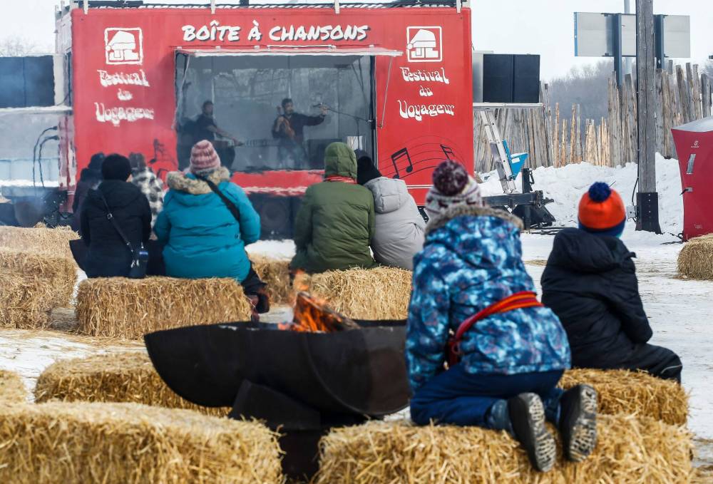 Visitors listen to musicians performing from Boîte à chansons, the festival‘s mobile concert trailer. (John Woods / Free Press)