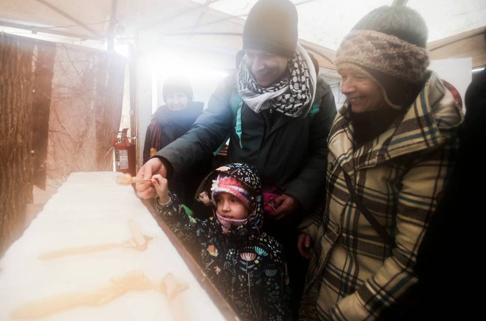 Stephanie (from left), Mark, along with children Charlotte and Jasper and their grandmother Sondra (right) roll maple taffy. (John Woods / Free Press)
