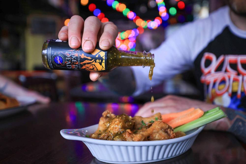 RUTH BONNEVILLE / FREE PRESS
Josh Ayers pours Intergalactic Sauces’ Wake the Dead concoction — a vegan, smoked
honey-dill hot sauce specially created for Winnipeg punk band Comeback Kid.