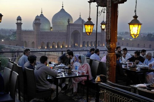 FILE - People break their fasts during the Muslim's holy fasting month of Ramadan, at a rooftop restaurant near the historical Badshahi mosque, in background, in Lahore, Pakistan, March 15, 2024. (AP Photo/K.M. Chaudary, File)