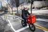 FILE - A delivery worker rides his bicycle along a path on the West Side Highway in New York, March 16, 2020. (AP Photo/John Minchillo, File)