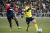 Nashville SC midfielder Alex Muyl (19) kicks the ball past New England Revolution defender Mamadou Fofana, left, during the second half of an MLS soccer match Saturday, Feb. 22, 2025, in Nashville, Tenn. (AP Photo/George Walker IV)