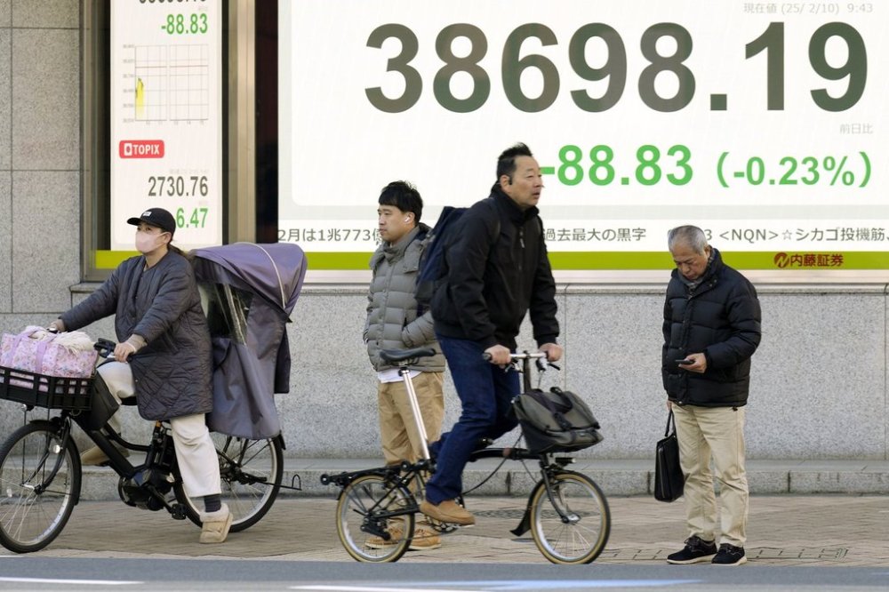 People stand in front of an electronic stock board showing Japan's Nikkei index at a securities firm Monday, Feb. 10, 2025, in Tokyo. (AP Photo/Eugene Hoshiko)